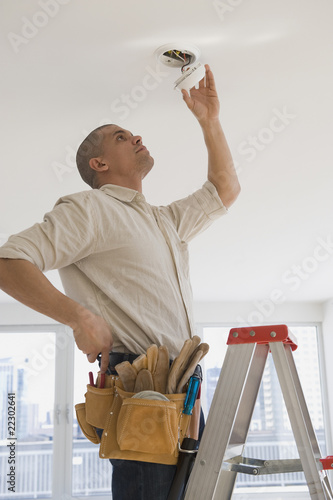 Hispanic male electrician fixing looking at wiring photo