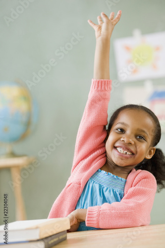 Mixed race girl raising hand to answer question photo