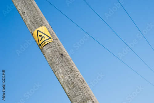 Danger of electrocution sign on electric pole on blue sky