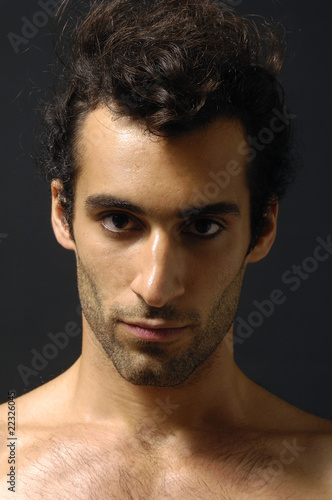 portrait of young serious man on black