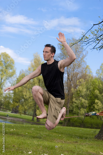 Mann hockt auf Slackline