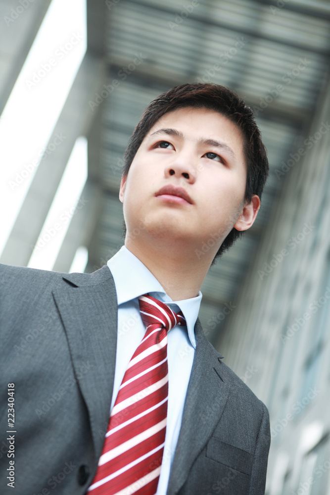 a yong Asiatic businessman is standing outdoor a yong Asiatic businessman is standing outdoor