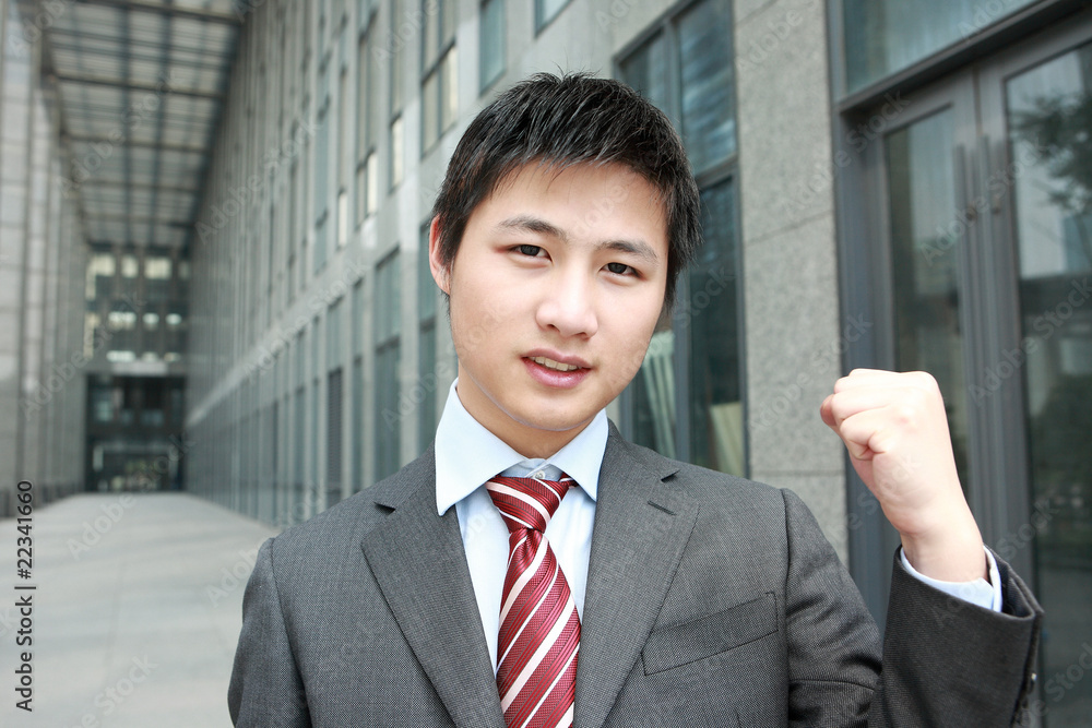 a yong Asiatic businessman is standing outdoor a yong Asiatic businessman is standing outdoor