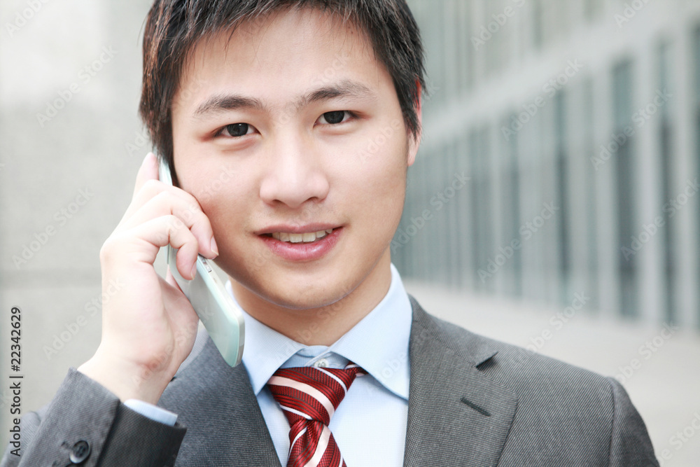 a yong Asiatic businessman is answering phone outdoor a yong Asiatic businessman is answering phone outdoor