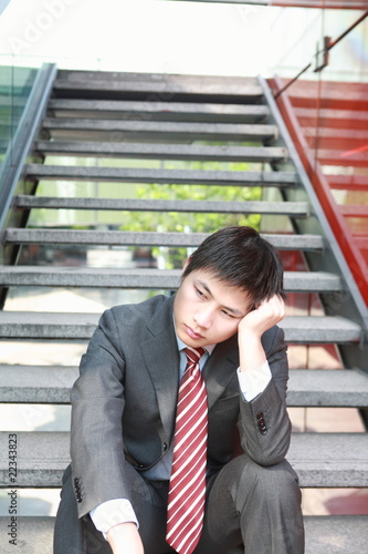 a yong Asiatic businessman is thinking something outdoor