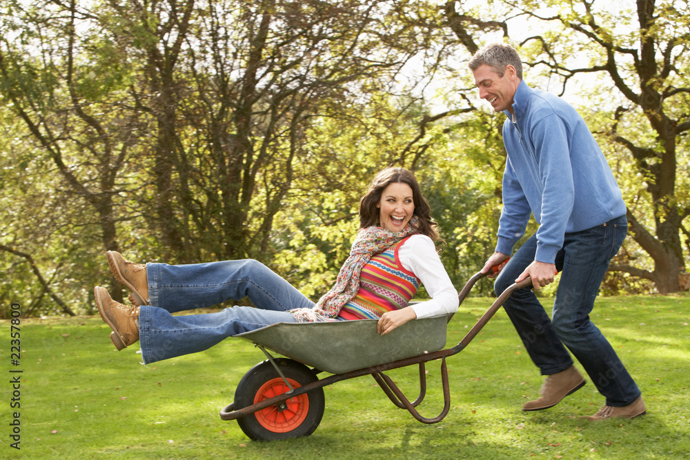 Couple With Man Giving Woman Ride In Wheelbarrow Couple With Man Giving Woman Ride In Wheelbarrow