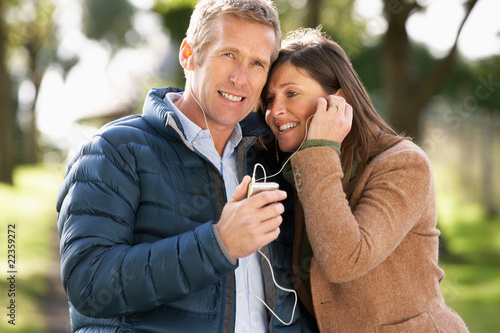 Couple Listening To MP3 Whilst Walking In Autumn Park © micromonkey