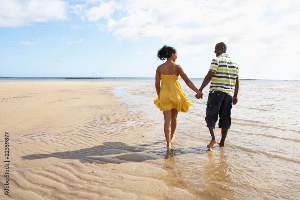 Romantic Young Couple Walking Along Shoreline Of Beach Holding H Romantic Young Couple Walking Along Shoreline Of Beach Holding H
