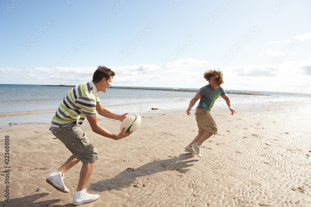 Two Teenage Boys Playing Rugby On Beach Together Two Teenage Boys Playing Rugby On Beach Together