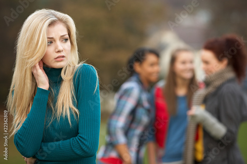 Upset Teenage Girl With Friends Gossiping In Background