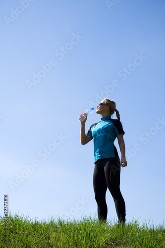 Young woman drinking water during running