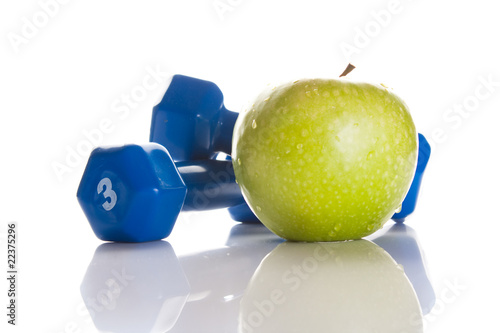 Dumbbells and a green fresh apple isolated on white