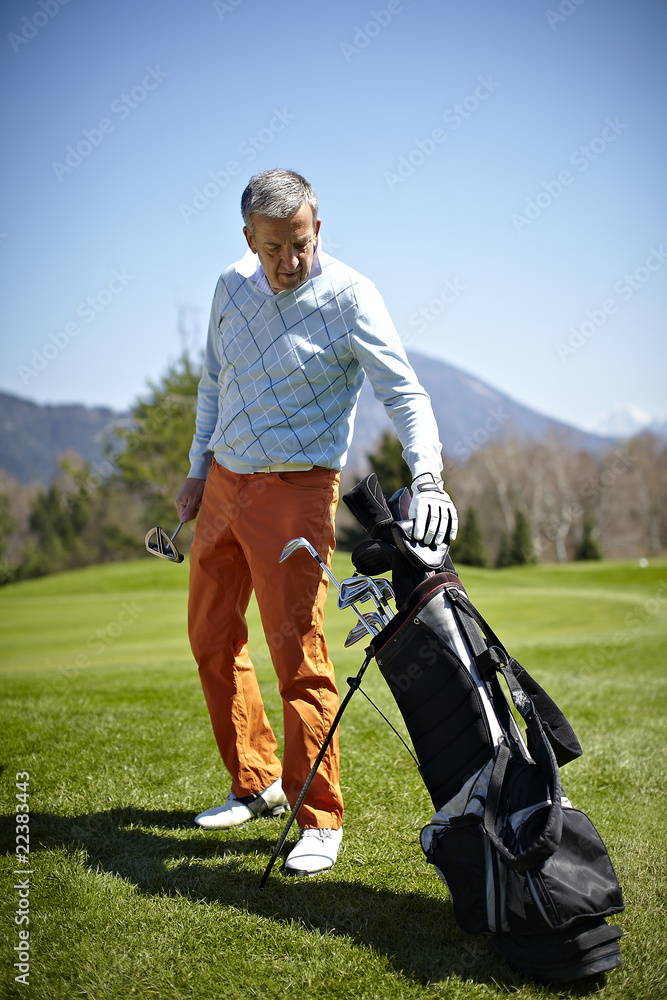 Man with a golf club and bag on the green