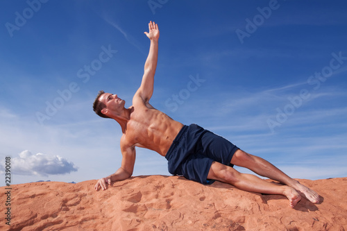 Man doing yoga on red rocks