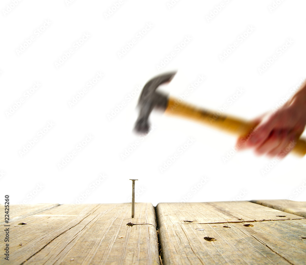 nail in wood being pounded by a hammer
