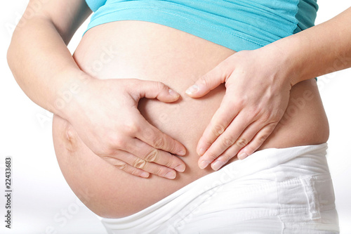 schwangere Frau formt ein Herz mit ihren Händen