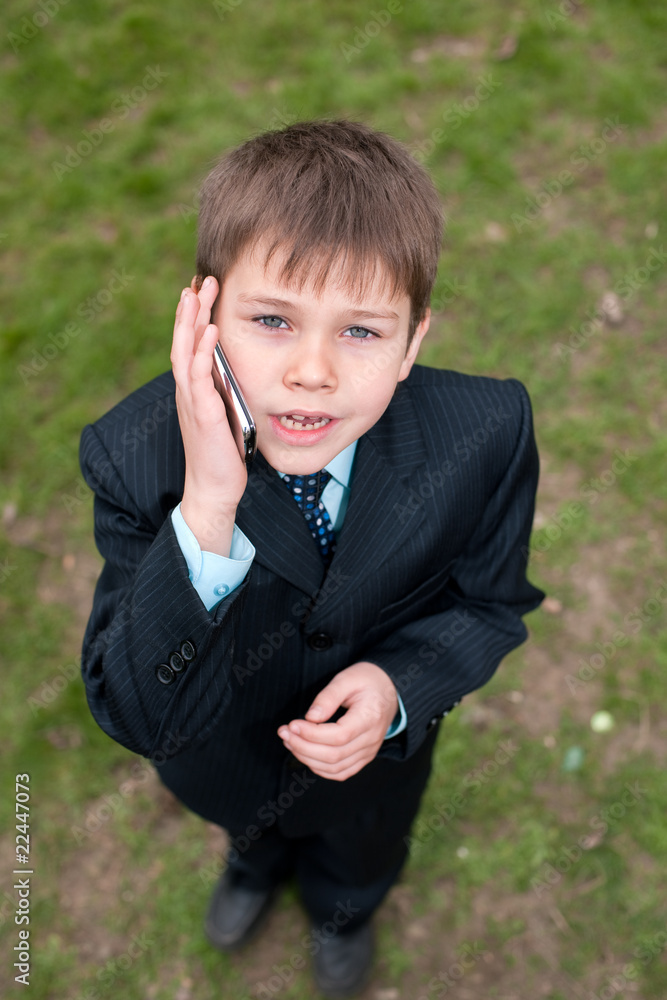 Serious boy in suit speaking over the mobile Serious boy in suit speaking over the mobile