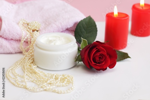 Container of cosmetic cream with rose and pearl necklace