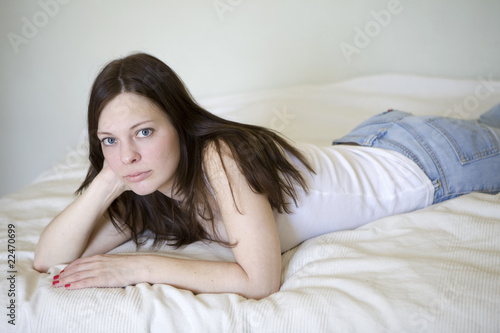 young serious woman lying on bed