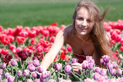 young happy girl in red and purple tulips