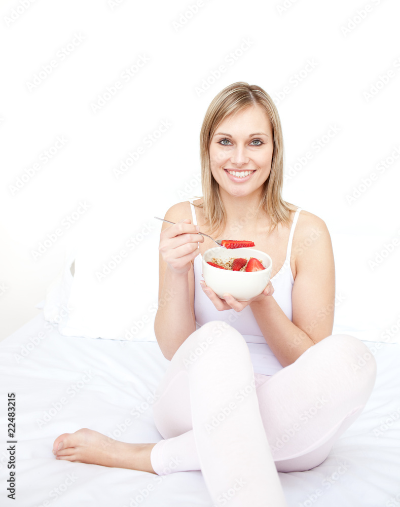 Delighted woman eating cereals with strawberries Delighted woman eating cereals with strawberries
