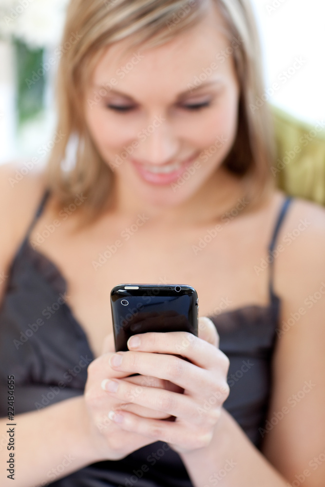Young woman sending a text sitting on a sofa Young woman sending a text sitting on a sofa