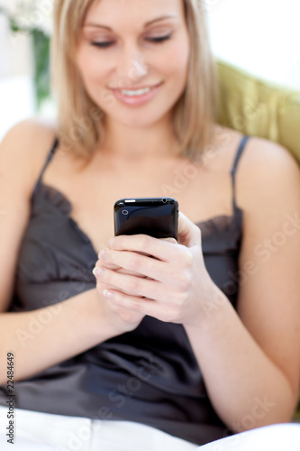 Blond woman sending a text sitting on a sofa