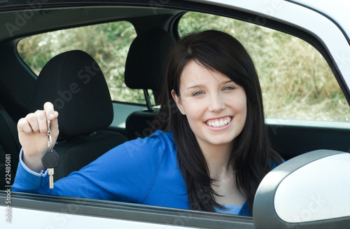 Jolly teen girl sitting in her car holding keys