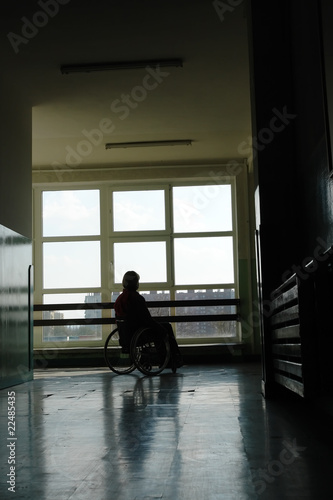 Silhouette of wheelchair woman looking through window © Roman Milert
