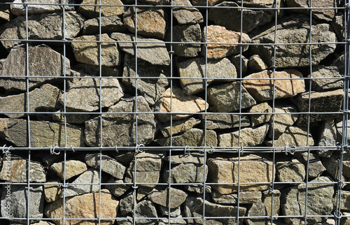 Fragment of wall made of wired cage filled with stones (gabions) photo