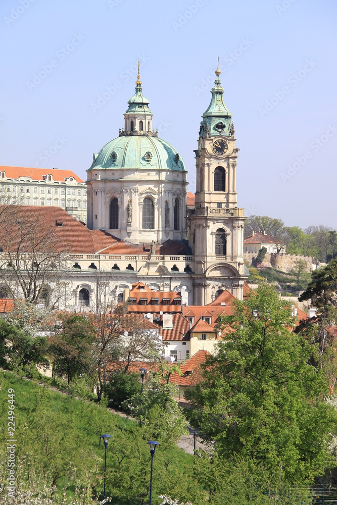 Prague's St. Nicholas' Cathedral with flowering trees and grass