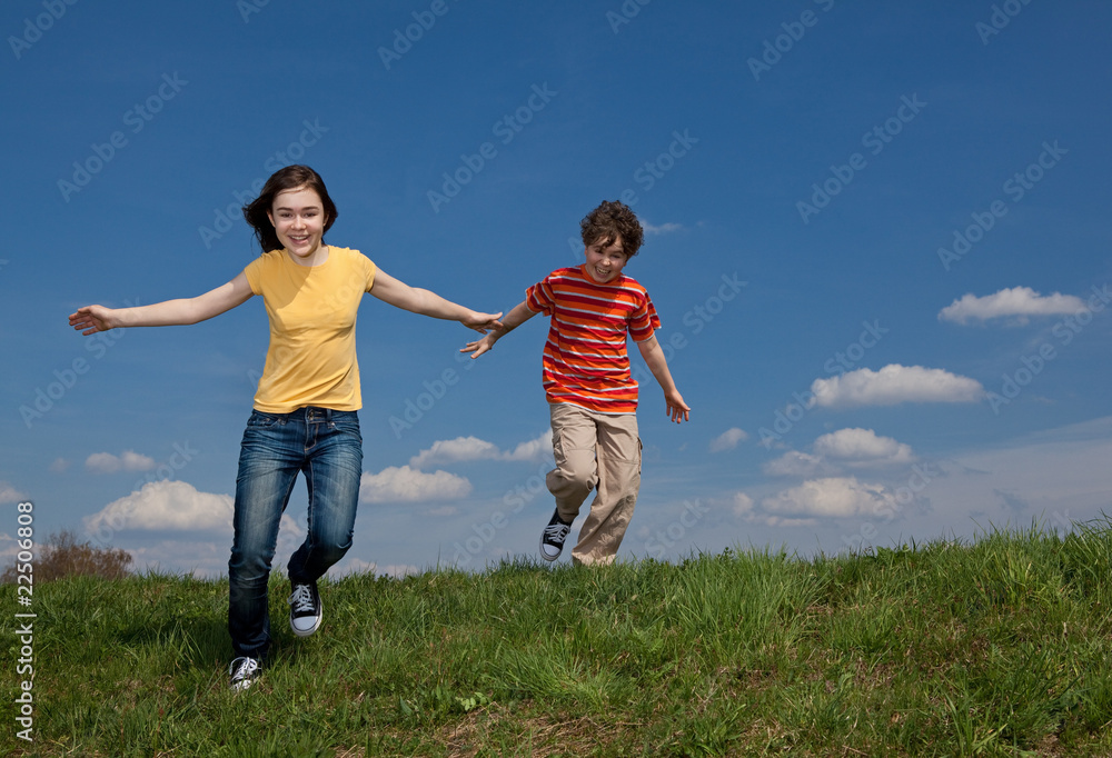 Girl and boy jumping, running against blue sky Girl and boy jumping, running against blue sky