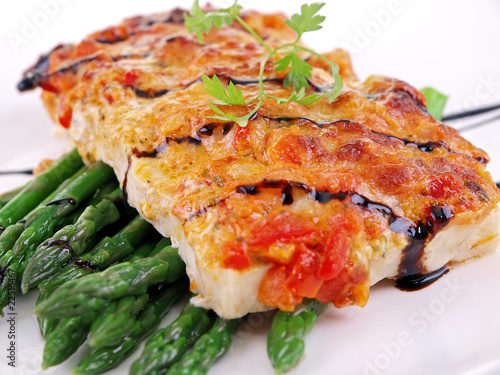 baked fish with green asparagus on white background