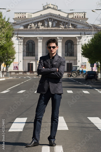 Young cofident man standing on the road with arms crossed photo