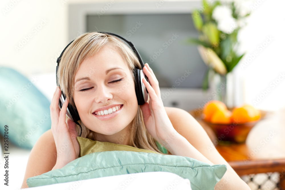 Naklejka premium Delighted young woman listening music lying on a sofa