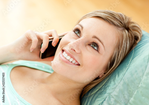 Jolly young woman talking on phone lying on a sofa