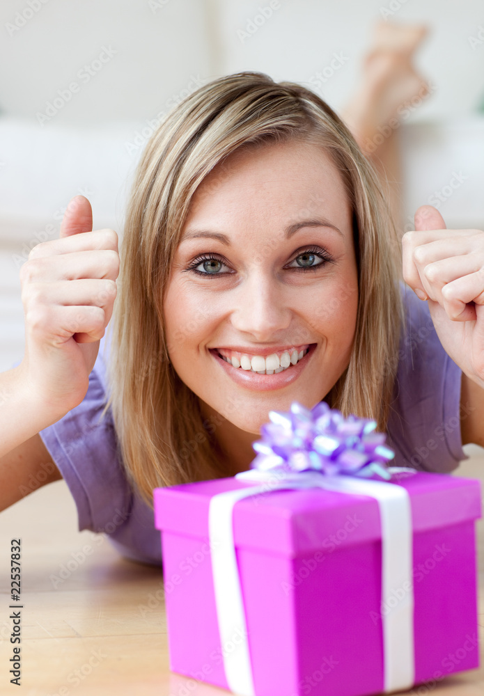 Excited woman looking at a gift lying on the floor Excited woman looking at a gift lying on the floor