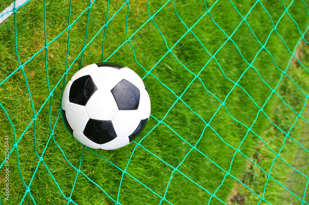 Naklejka premium Soccer ball in the goal net