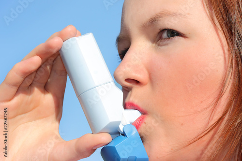 Teenage girl using inhaler outdoors