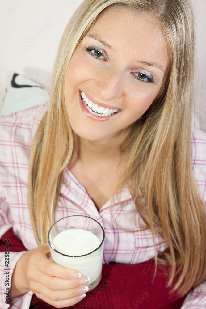 Woman in pajama in bed with glass of milk