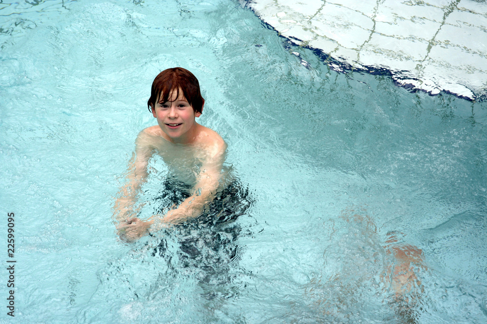 young boy has fun in the public indoor pool