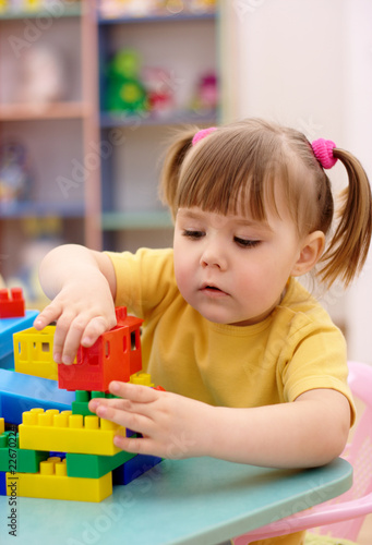 Little girl play with building bricks in preschool