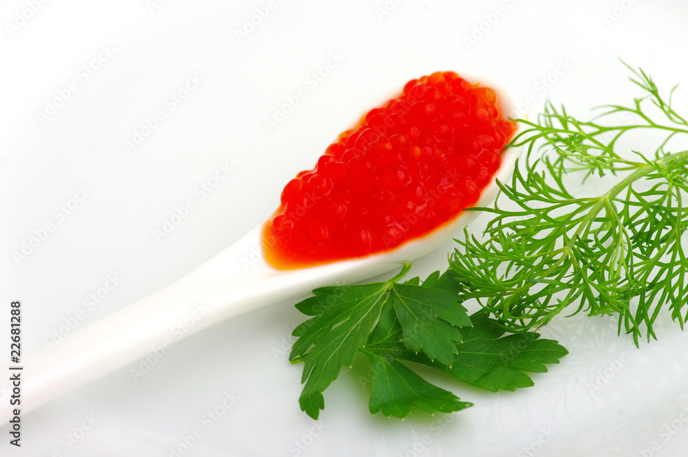 Spoon with red caviar and greens parsley on a white plate Spoon with red caviar and greens parsley on a white plate