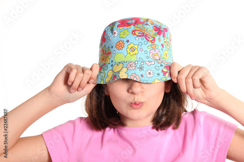 bambina spiritosa con cappello colorato sugli occhi photo