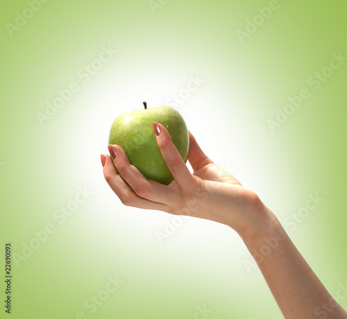 A green tasty apple held in a young female hand