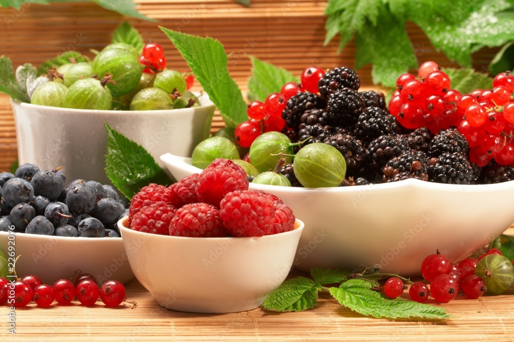 Berries in plates, on a table, among green leaves Berries in plates, on a table, among green leaves
