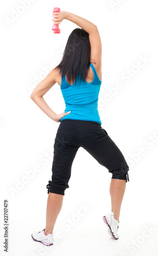 Back of woman standing and exercising with dumbbell