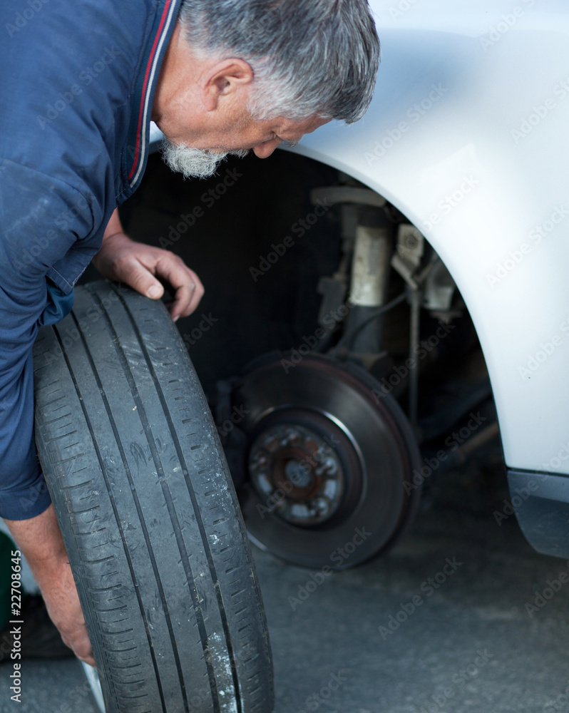 mechanic changing a wheel of a modern car (color toned image) mechanic changing a wheel of a modern car (color toned image)