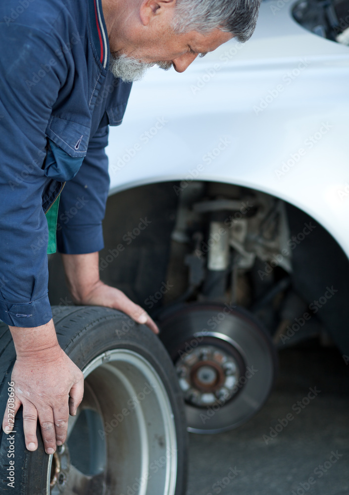 mechanic changing a wheel of a modern car (color toned image) mechanic changing a wheel of a modern car (color toned image)