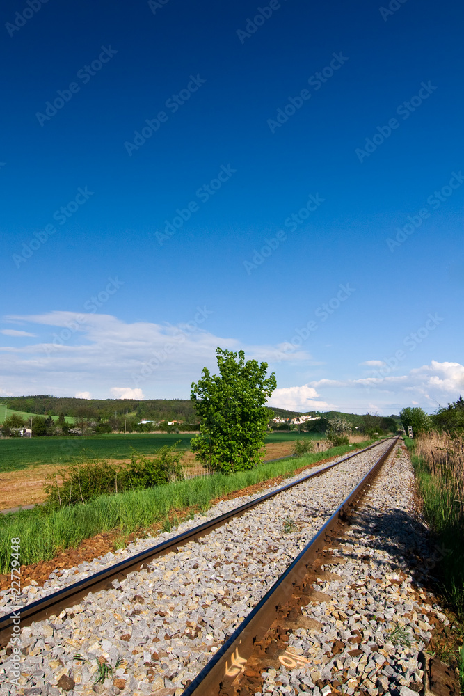 Fototapeta premium Spring countryside with railway and blue sky